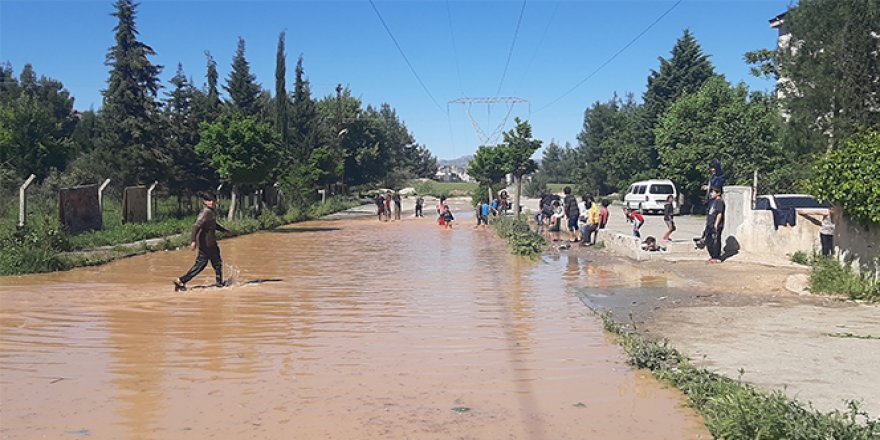 Çocukların patlayan borudan akan suda çamurla oyunu